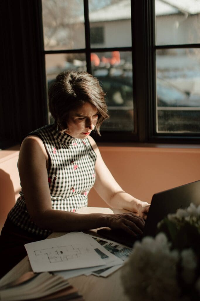 Interior designer with laptop and design documents on table