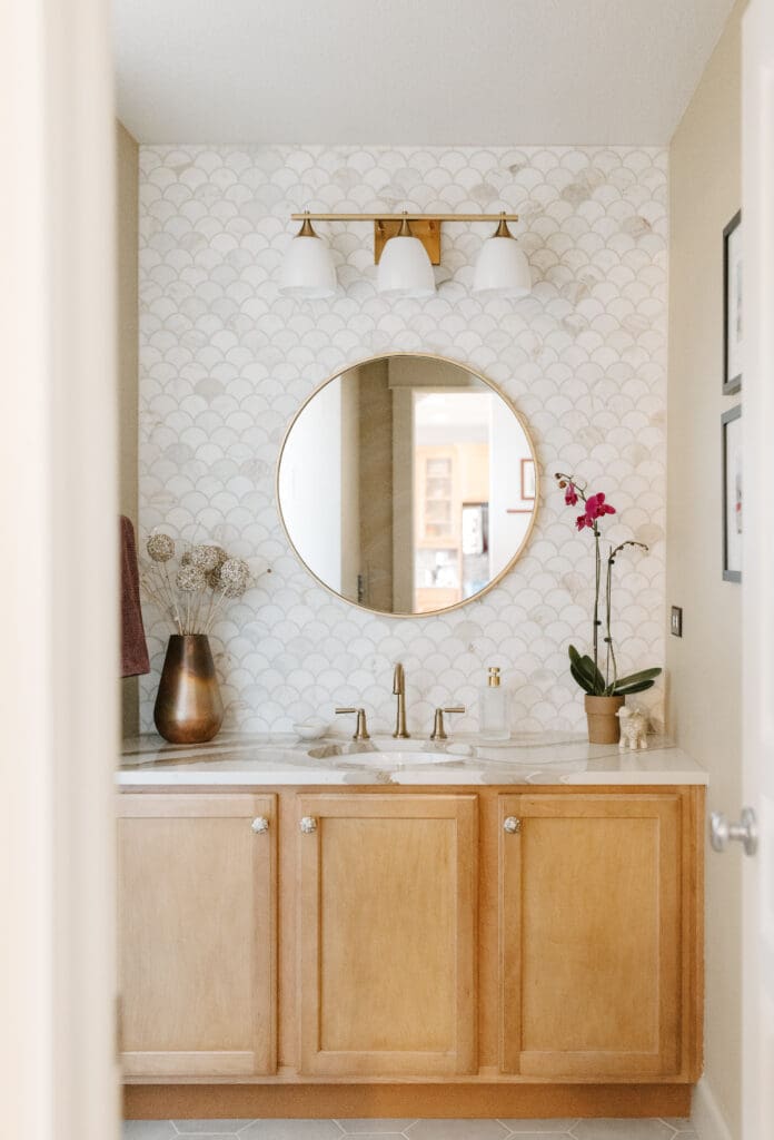 Powder bathroom with warm wood, Mother-of-Pearl hardware, copper accessories, brass plumbing and lighting fixtures, Cambria quartz counter, and marble wainscot tile