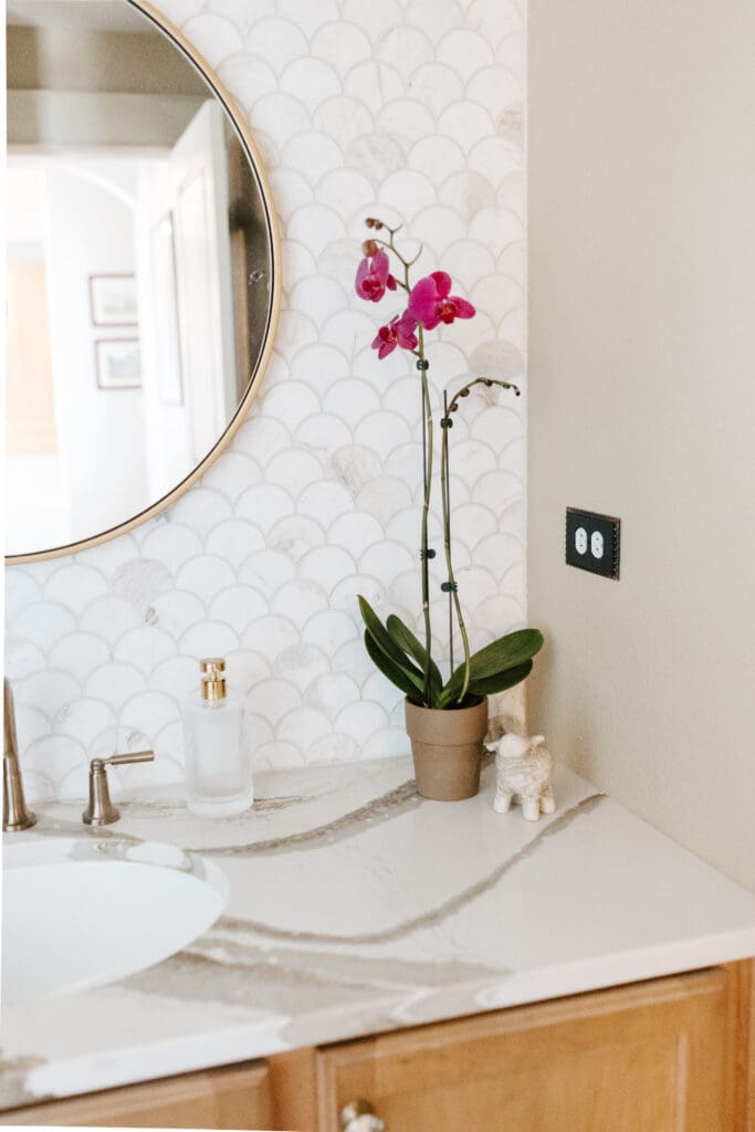 Powder bathroom with warm wood, Mother-of-Pearl hardware, copper accessories, brass plumbing and lighting fixtures, Cambria quartz counter, and marble wainscot tile