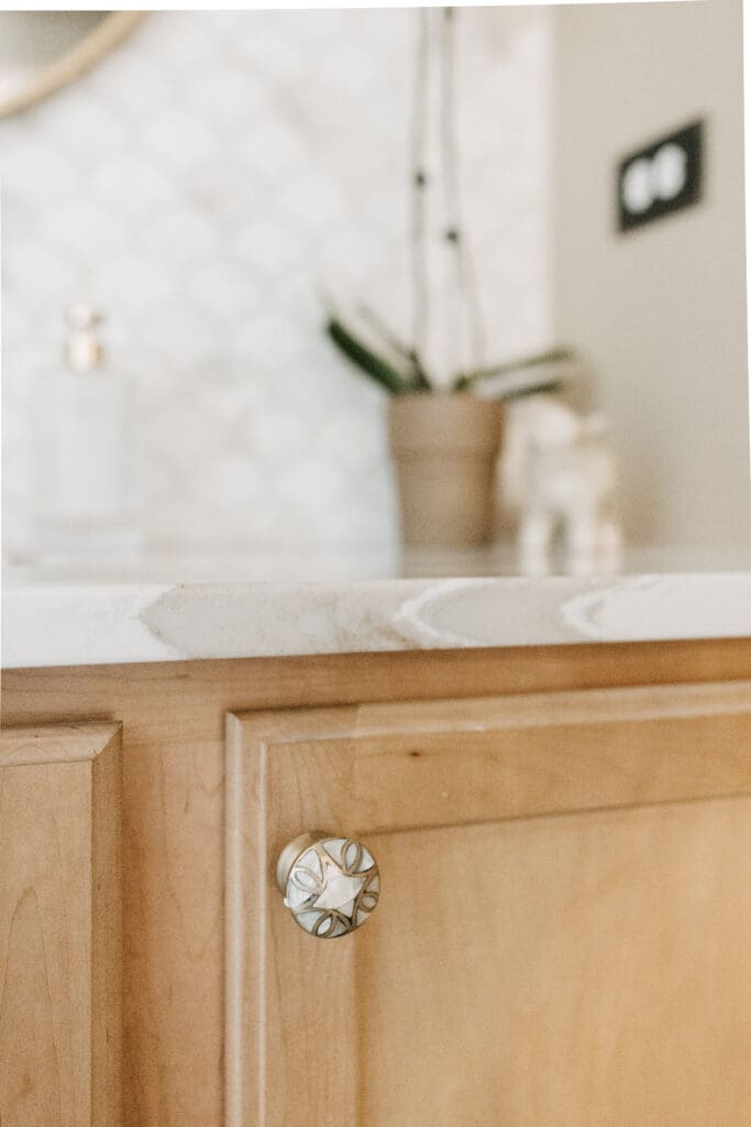 Powder bathroom with warm wood, Mother-of-Pearl hardware, copper accessories, brass plumbing and lighting fixtures, Cambria quartz counter, and marble wainscot tile