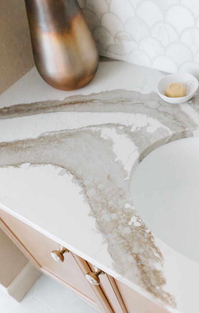 Powder bathroom with warm wood, Mother-of-Pearl hardware, copper accessories, brass plumbing and lighting fixtures, Cambria quartz counter, and marble wainscot tile