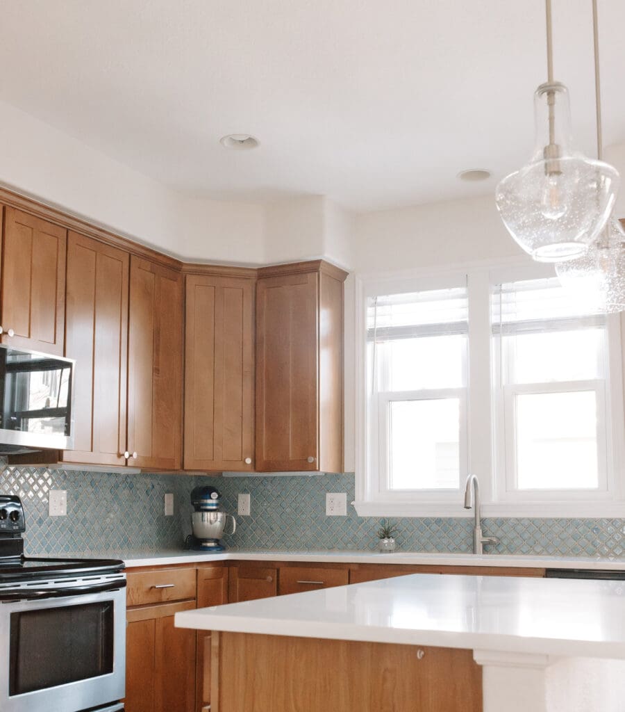 Kitchen Mini-Remodel with quartz countertops, blue arabesque backsplash tile, and seedy glass pendants
