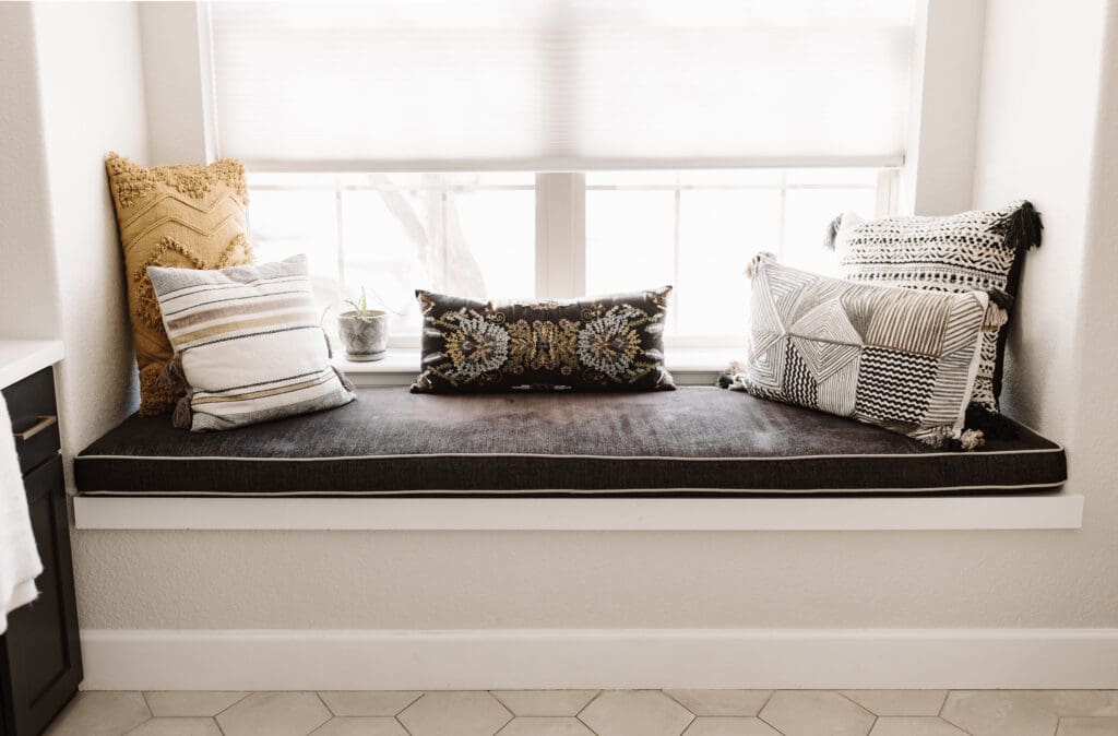 Window seat with black Kravet cushion and colorful, textural Loloi pillows